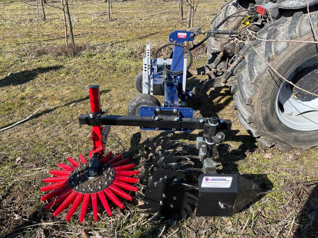 Máquina Klaudia conectada a tractor agrícola durante escarda entre árboles frutales